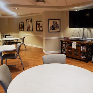 A cozy dining area featuring tables and chairs, decorated with artwork and complemented by a television.