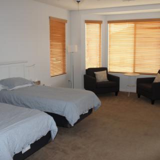 A cozy bedroom with two twin beds and a seating area by the window.