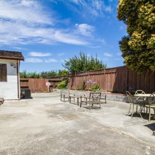 A sunny backyard patio with outdoor furniture and a wooden fence.