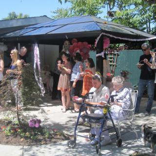 A group of people enjoy a sunny outdoor gathering in a garden setting.