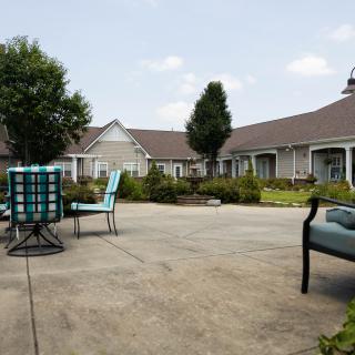 A spacious outdoor patio with chairs and tables surrounded by a building and trees.