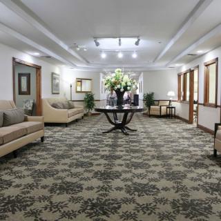 A spacious hotel lobby featuring elegant furniture and a central table adorned with floral arrangements.