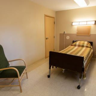 A simple and clean hospital patient room featuring a bed and a chair.