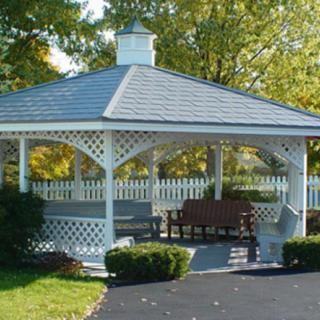 A scenic view of a gazebo with a bench surrounded by greenery.