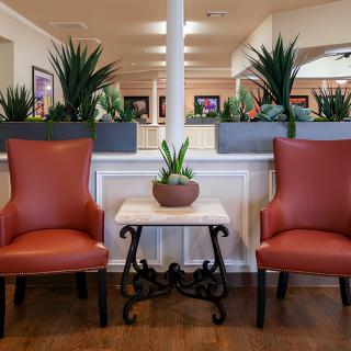 A well-decorated seating area with two red chairs and plants.