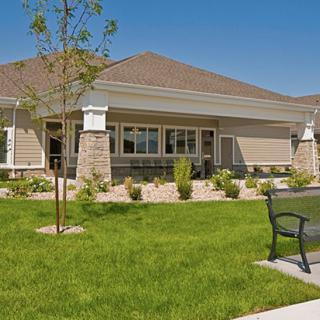 A modern house with a landscaped lawn and a bench in the foreground.