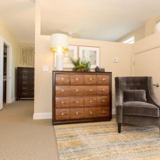 A cozy bedroom with a dresser, armchair, and stylish decor.