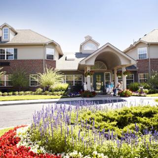 A beautifully landscaped entrance to a residential building with vibrant flowers and greenery.