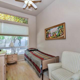 A cozy bedroom with a single bed and large windows allowing natural light in.