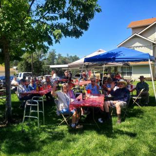 A group of people enjoying a sunny outdoor gathering under a canopy.