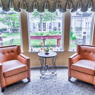 A cozy seating area with two leather chairs and a small table by the window, overlooking a garden.