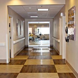 A well-lit office hallway with checkered flooring and artwork on the walls.
