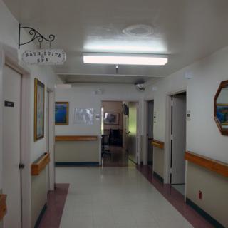 A hospital hallway with doors on either side and bright overhead lighting.