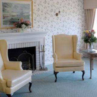 A cozy living room with traditional armchairs and a fireplace.