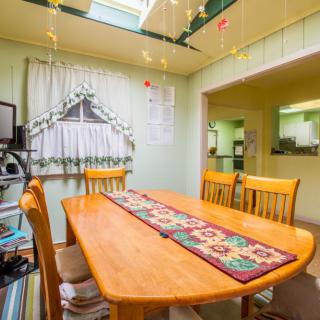A cozy dining room with a wooden table, chairs, and a colorful table runner under a skylight.
