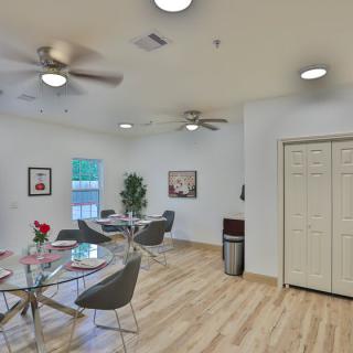 A modern dining area with stylish tables and chairs, featuring ceiling fans and ample natural light.