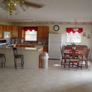 A spacious kitchen and dining area with wooden cabinets, a central table, and modern appliances.