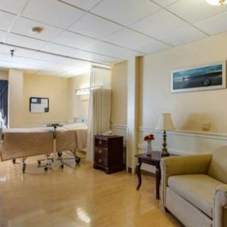 A clean and well-furnished hospital room with a patient bed and seating area.