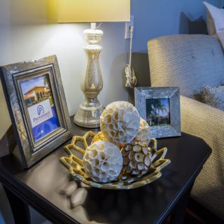 A cozy living room table with a lamp, decorative bowl, and framed photos.