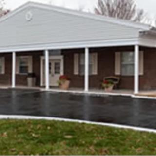 A brick building with white columns and a paved driveway.