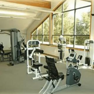 A well-lit gym with various fitness equipment and large windows providing natural light.