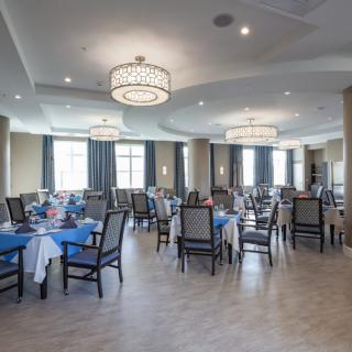 A spacious dining room with elegantly set tables and modern chandeliers.