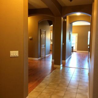 A warm-toned hallway in a house featuring tile and wooden flooring with archways.