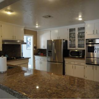 Modern kitchen with stainless steel appliances and marble countertops.