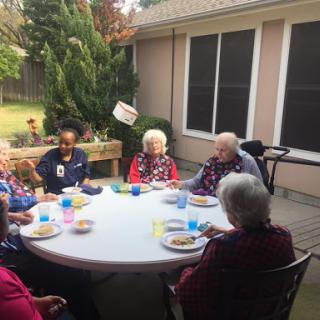 Seniors enjoying a meal and conversation together outside.