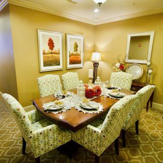 A warmly decorated dining room with a wooden table and patterned chairs, complemented by artwork on the walls.