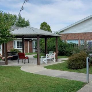 A peaceful garden area with a gazebo, benches, and a pathway adjacent to a building.