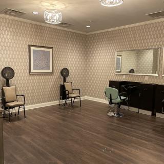 An elegant salon interior with chairs, mirrors, and hair drying stations.