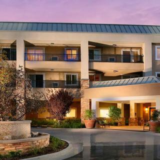 Modern hotel exterior at dusk with well-lit entrance and landscaping.