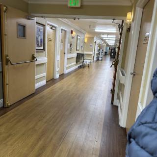 A well-lit hallway with wooden flooring and art on the walls.