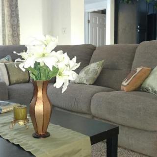 A cozy living room setup with a gray couch and a vase of white flowers on the coffee table.