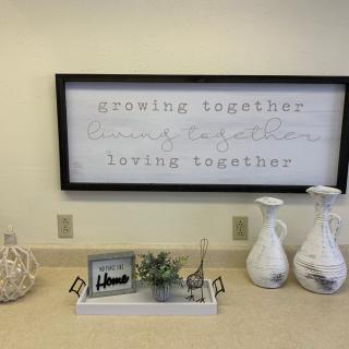A cozy home setup with a framed sign saying 'growing together, living together' alongside decorative vases and a centerpiece on a tray.