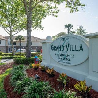 The entrance to Grand Villa Assisted Living Residence featuring well-maintained landscaping and clear signage.