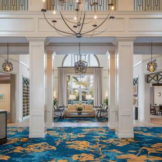 A luxurious hotel lobby featuring elegant chandeliers, a vibrant carpet, and a cozy seating area.