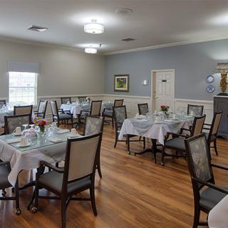 An elegantly arranged dining room with neatly set tables and chairs on a polished wooden floor.