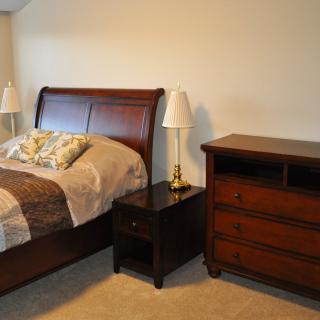 A cozy bedroom with a wooden bed, nightstand, and dresser.