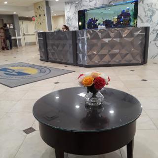 A view of a hotel lobby featuring a reception desk and a decorative table with flowers.