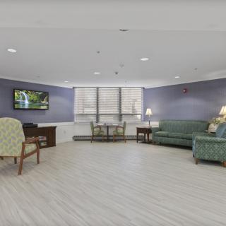 A spacious living room with a sofa, chairs, a table, and a mounted television.
