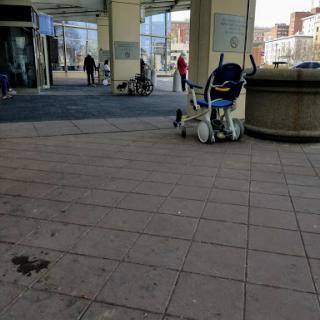 A quiet moment at a shopping center entrance, featuring a stroller and people walking by.