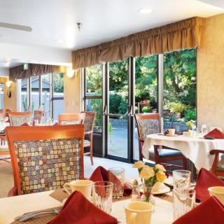 A serene restaurant dining area with elegantly set tables overlooking a lush garden through large windows.