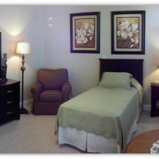 A cozy bedroom with a single bed, armchair, and decorative elements.