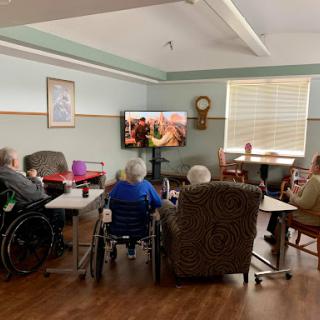 Elderly residents enjoying a movie together in a cozy common area.