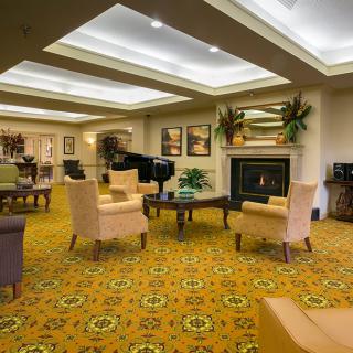 A cozy lounge with comfortable seating, a grand piano, and a warm fireplace.