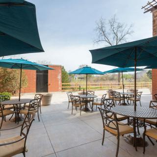 A patio area with tables, chairs, and umbrellas set against a brick building.