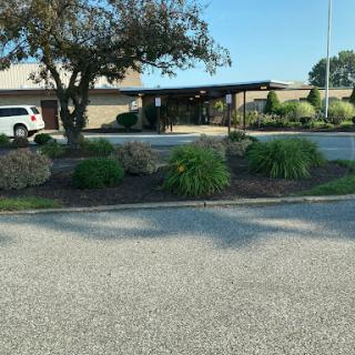 A view of a building with landscaped areas and a parking lot.