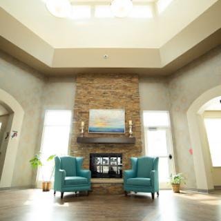 A cozy and inviting living room featuring teal armchairs, a stone fireplace, and ample natural light.